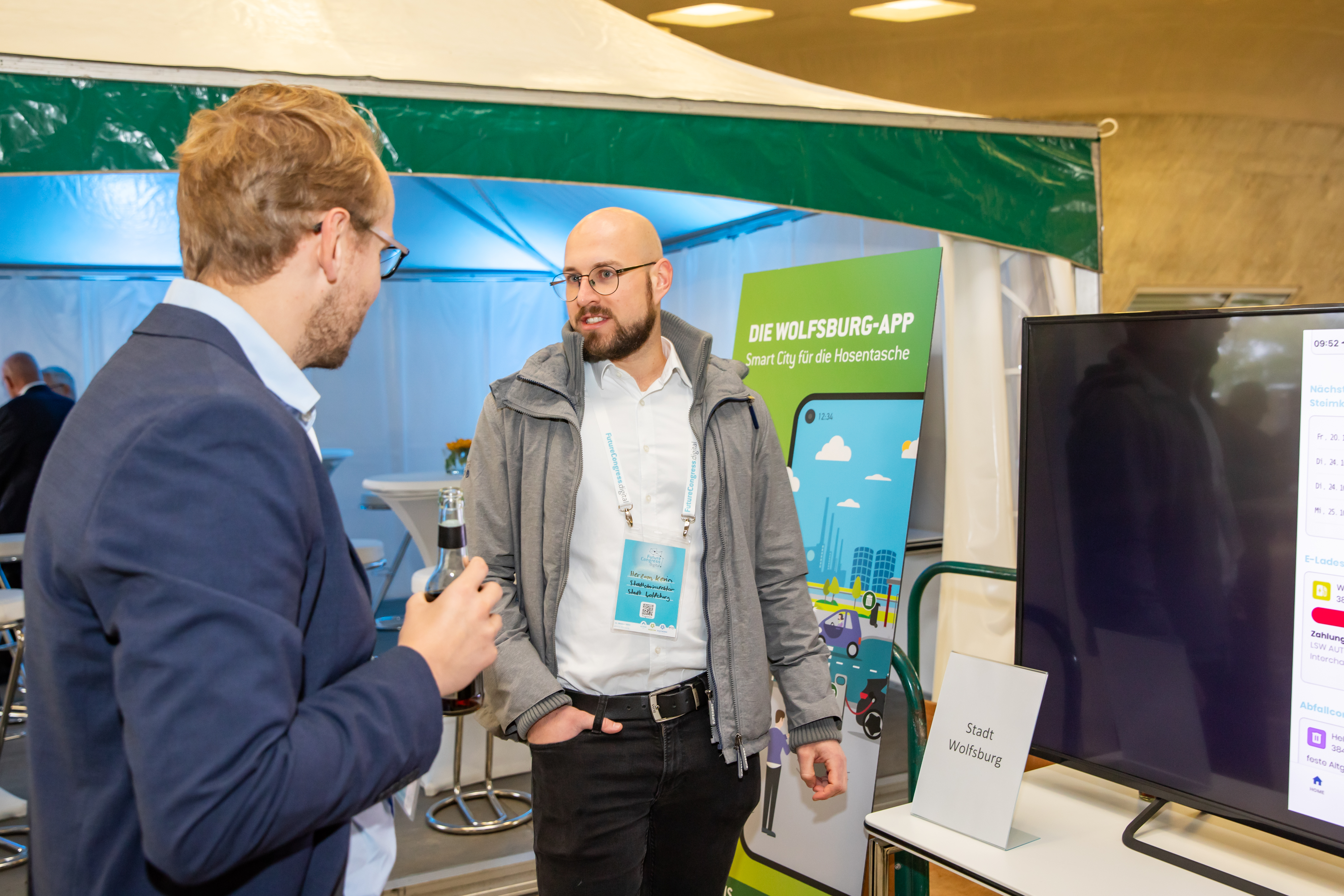 Zwei Männer Unterhalten sich vor dem Stand der Stadt Wolfsburg zur Wolfsburg App.